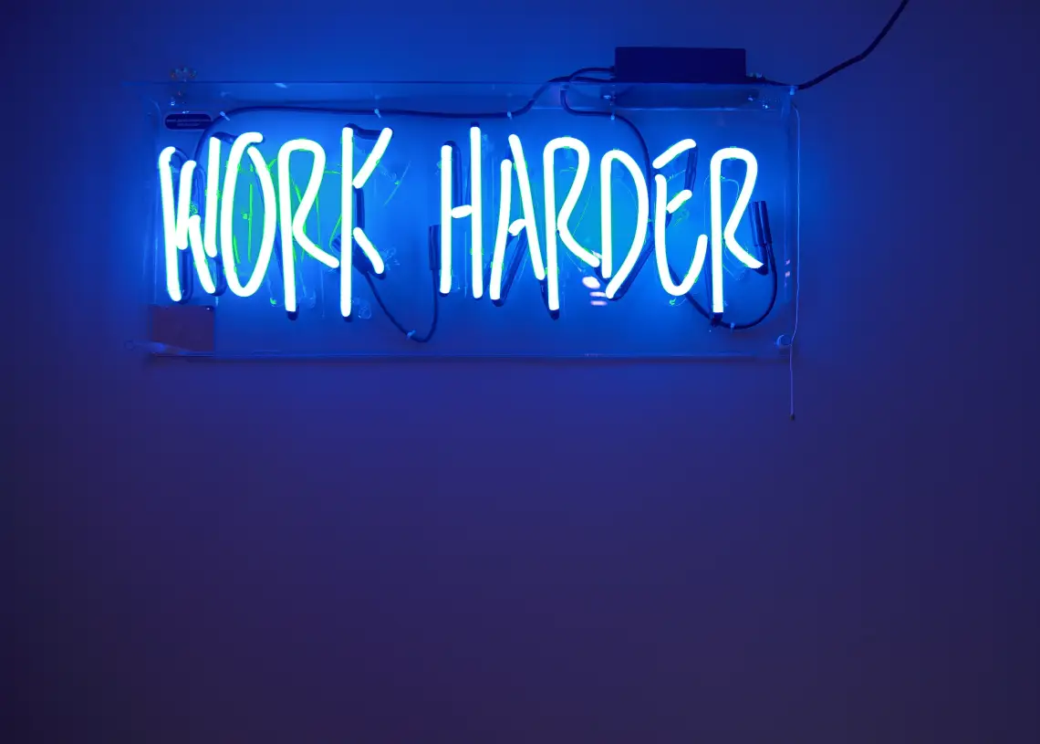 målsætningsteorien - her neonskilt på væg work harder