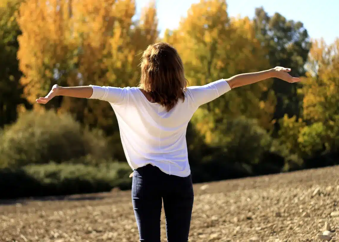 Hvad er motivation også - her en kvinde med armene i vejret i en skovlysning
